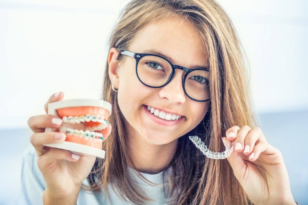 Dental invisible braces or silicone trainer in the hands of a young smiling girl. Orthodontic concept Invisalign